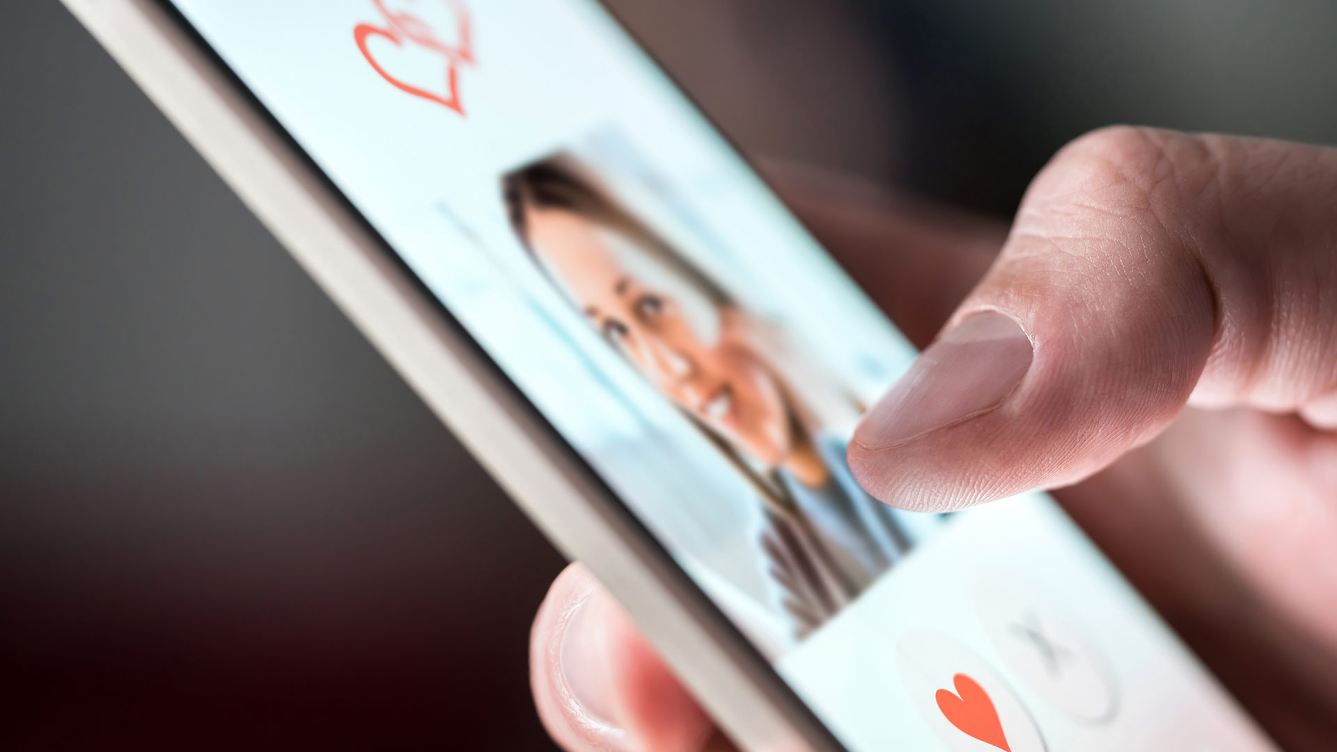 Mobile phone screen showing the image of an attractive woman smiling with a heart and cross buttons under it.