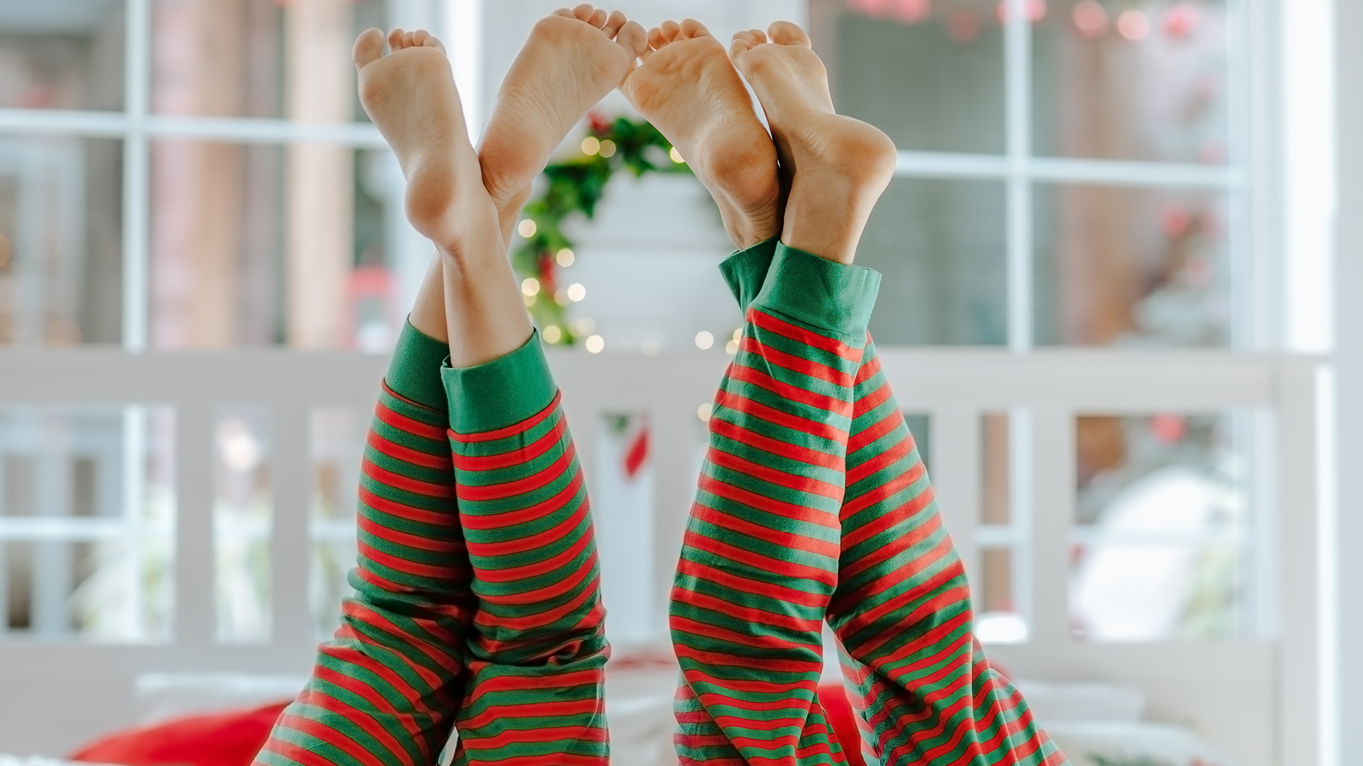 Upside down legs of a couple wearing matching red-green striped pyjamas.