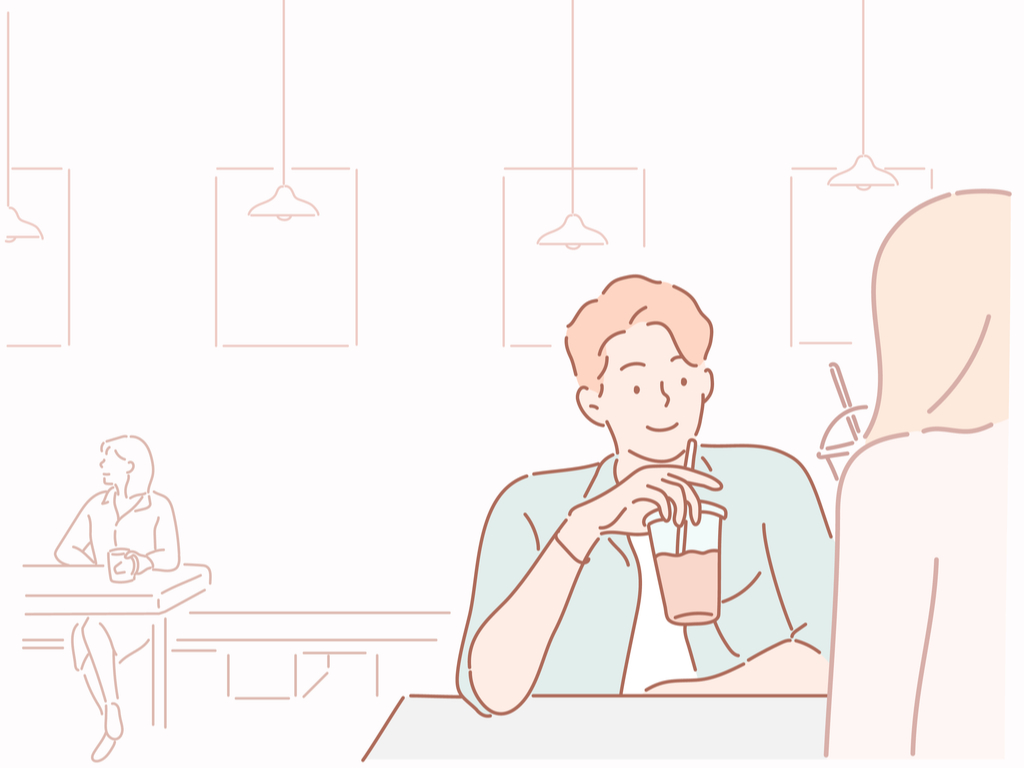 Ginger man and blonde woman sitting down, holding their drinks having a conversation while smiling.