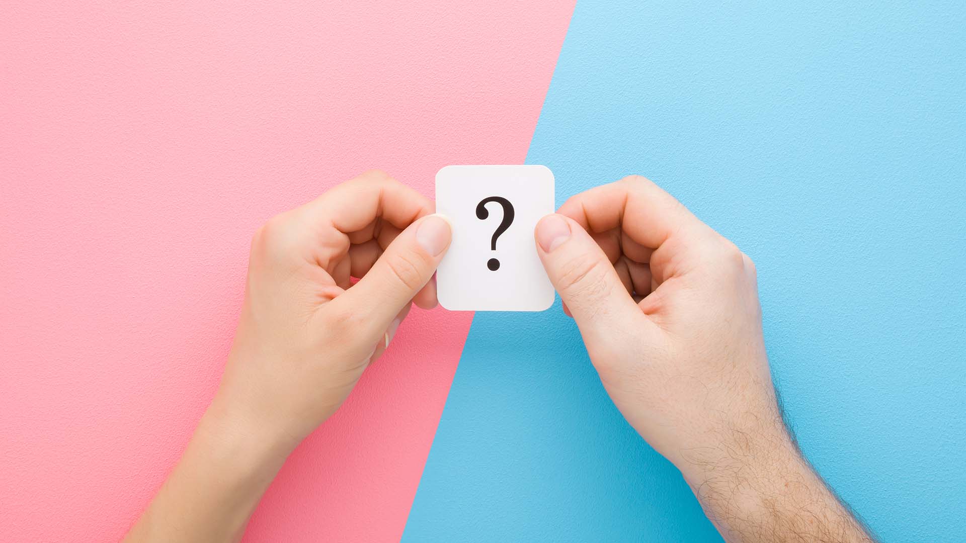 Two hands holding a card with a black question mark on it, background split between blue and pink.