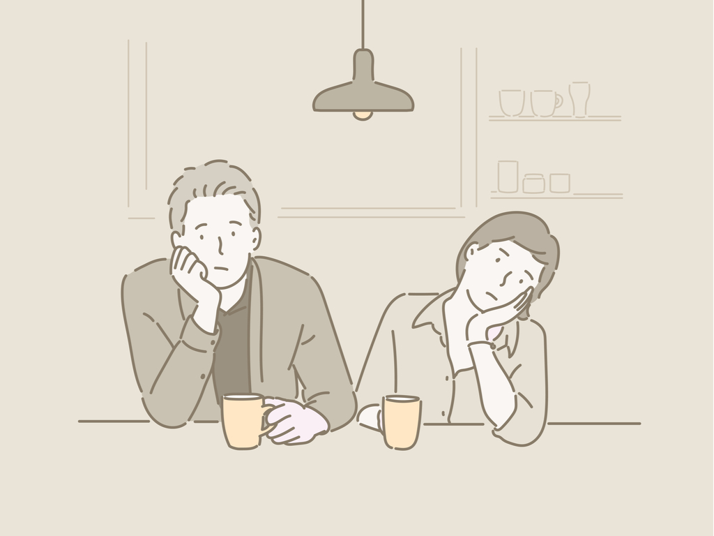 Man and woman sitting at a table with mugs in their hands both resting their heads in their palms and looking bored.